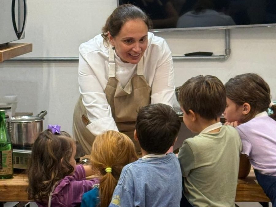 Educadora conduzindo uma aula com a turma em volta da bancada